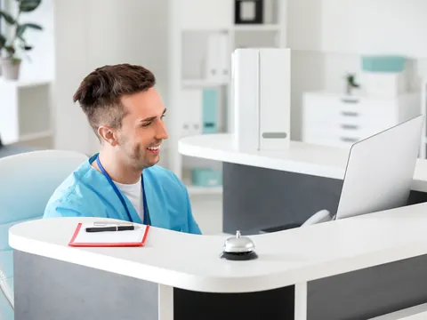 Recepcionista sorrindo no balcão de uma clínica