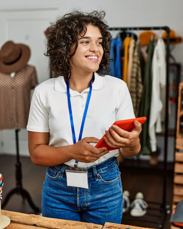 Dona de loja sorrindo com o celular na mão, no balcão