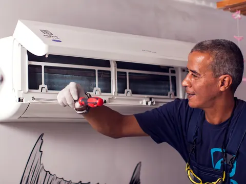 Técnico consertando um ar-condicionado split dentro de casa